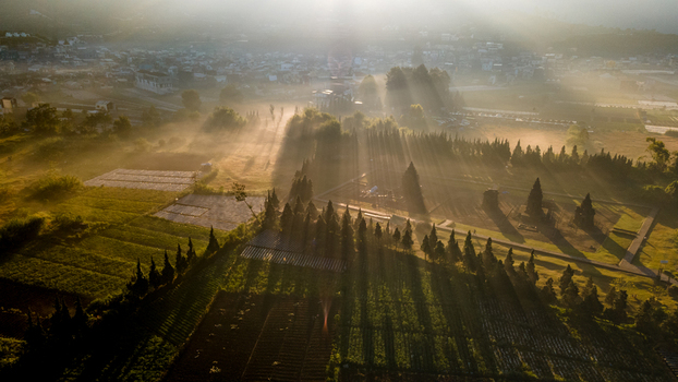Aerial view of Dieng Plateau with ancient temples lush agricultural fields and morning sun rays filtering through mist in Kecamatan Batur Jawa Tengah Indonesia. Aerial view of Dieng Plateau with ancient temples lush agricultural fields and morning sun rays filtering through mist in Kecamatan Batur Jawa Tengah Indonesia.