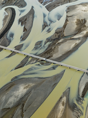 Aerial view of glacial rivers carving paths through the stark landscape bisected by a bridge Iceland Iceland. Aerial view of glacial rivers carving paths through the stark landscape bisected by a bridge Iceland Iceland.