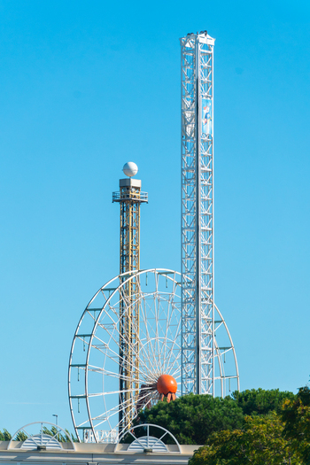 View of Azur Park featuring a large Ferris wheel and a tall drop tower against a clear blue sky in Gassin Provence Alpes Cote d Azur France. View of Azur Park featuring a large Ferris wheel and a tall drop tower against a clear blue sky in Gassin Provence Alpes Cote d Azur France.