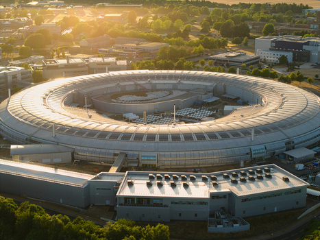 Aerial view of Diamond Light Source a circular synchrotron facility surrounded by greenery under golden hour light in Didcot United Kingdom.