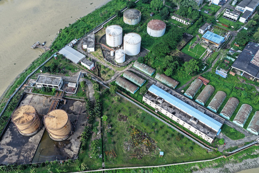 Aerial view of the industrial facility with large storage tanks and warehouses situated along the banks of the Karnaphuli River in Chattogram Chittagong Division Bangladesh.