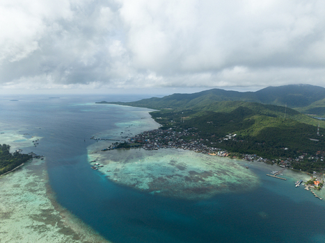 Aerial view of the coastline meets the turquoise sea near the town with lush mountains in the distance Karimunjawa Central Java Indonesia. Aerial view of the coastline meets the turquoise sea near the town with lush mountains in the distance Karimunjawa Central Java Indonesia.