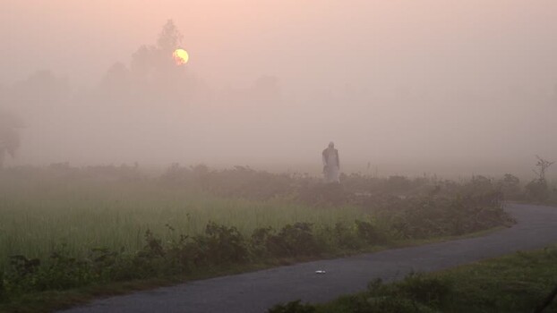 View of a person walking on a foggy road at sunrise Bangladesh.