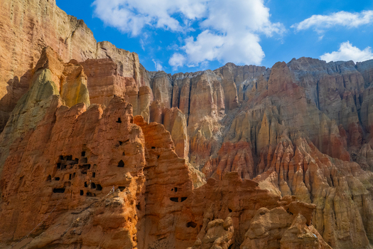 Aerial view of ancient cliff dwellings carved into the eroded red sandstone cliffs of the Mustang region in Nepal.