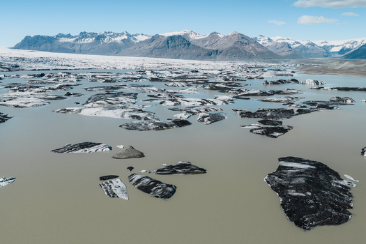 Aerial view of icebergs floating in the glacial lagoon of Fjallsarlon with snow capped mountains in the background Hornafjordur Iceland. Aerial view of icebergs floating in the glacial lagoon of Fjallsarlon with snow capped mountains in the background Hornafjordur Iceland.