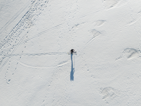 Aerial view of a lone skier standing on the snowy south slope of Mount Etna with long shadows and tracks in the snow in Nicolosi Sicilia Italy. Aerial view of a lone skier standing on the snowy south slope of Mount Etna with long shadows and tracks in the snow in Nicolosi Sicilia Italy.