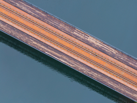 Aerial view of the historic railway truss bridge with weathered wooden planks and rusted metal tracks over water in Rutki Pomeranian Voivodeshi Poland. Aerial view of the historic railway truss bridge with weathered wooden planks and rusted metal tracks over water in Rutki Pomeranian Voivodeshi Poland.