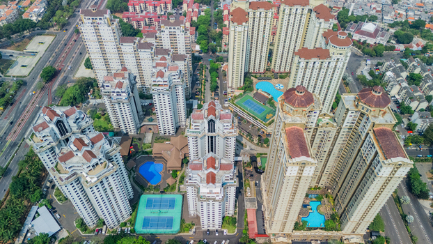 Aerial view of a modern high rise apartment complex featuring multiple residential towers swimming pools and tennis courts in the urban landscape of Jakarta Indonesia. Aerial view of a modern high rise apartment complex featuring multiple residential towers swimming pools and tennis courts in the urban landscape of Jakarta Indonesia.