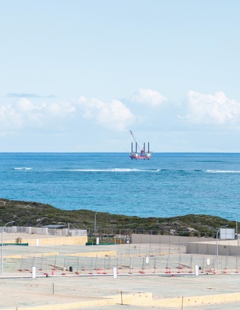 Aerial view of an offshore jack up rig stationed in the ocean near the coast with construction fencing in the foreground in Perth Western Australia Australia. Aerial view of an offshore jack up rig stationed in the ocean near the coast with construction fencing in the foreground in Perth Western Australia Australia.