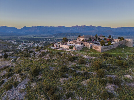 Aerial view of Lekuresi Castle on a hilltop overlooking the town featuring stone walls and historic architecture with distant mountains in Saranda Vlore County Albania. Aerial view of Lekuresi Castle on a hilltop overlooking the town featuring stone walls and historic architecture with distant mountains in Saranda Vlore County Albania.