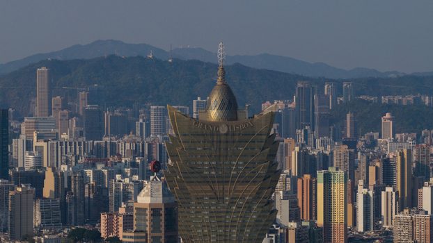 Macao 18 February 2026 Aerial view of the Grand Lisboa hotel rising above the dense urban skyline of Macau with mountains in the background under a clear sky. Macao 18 February 2026 Aerial view of the Grand Lisboa hotel rising above the dense urban skyline of Macau with mountains in the background under a clear sky.