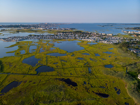 Ocean City Maryland United States 28 July 2019 Aerial view of the coastal marshlands and wetlands with residential developments in the distance under a clear sky.