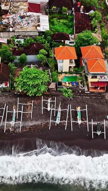 Aerial view of traditional boats on a black sand beach Indonesia.