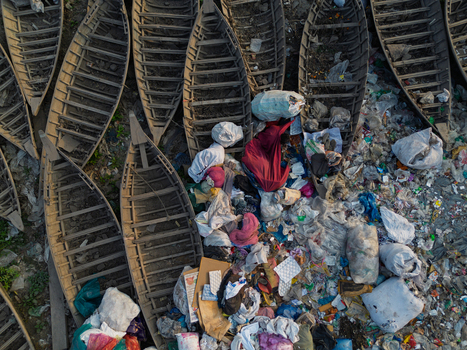 Dhaka Division Bangladesh 23 January 2026 Aerial view of wooden boats on the banks of the Buriganga River surrounded by piles of plastic waste and environmental pollution.