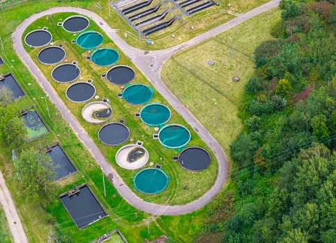 Aerial view of a trout aquaculture facility featuring circular fish tanks and rectangular ponds surrounded by lush green vegetation in Pomeranian Voivodeship Poland. Aerial view of a trout aquaculture facility featuring circular fish tanks and rectangular ponds surrounded by lush green vegetation in Pomeranian Voivodeship Poland.