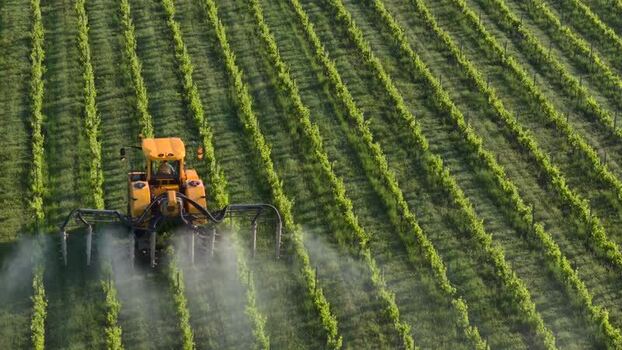 Aerial view of tractor spraying vineyard in Targon France.