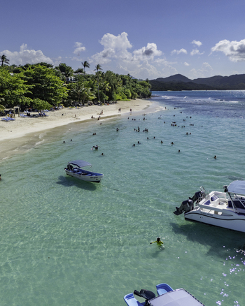 Aerial view of Javo Beach La Playita with turquoise water anchored boats and people swimming along the sandy shore in Las Galeras Las Galeras Dominican Republic. Aerial view of Javo Beach La Playita with turquoise water anchored boats and people swimming along the sandy shore in Las Galeras Las Galeras Dominican Republic.