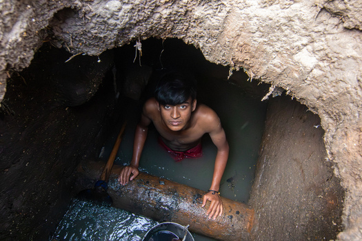 Dhaka Bangladesh 18 April 2018 View of a young worker inside a narrow water filled sewer hole looking up from the muddy underground drainage system. Dhaka Bangladesh 18 April 2018 View of a young worker inside a narrow water filled sewer hole looking up from the muddy underground drainage system.