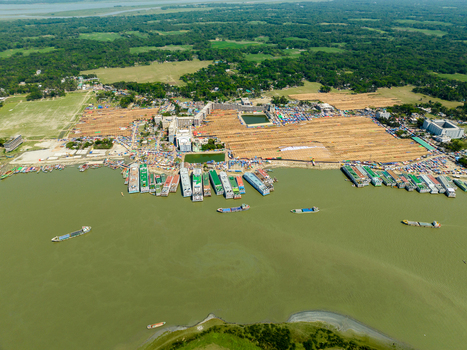 Aerial view of boats docked along the riverbank next to an area with numerous buildings and many people Charmonai Barisal Division Bangladesh. Aerial view of boats docked along the riverbank next to an area with numerous buildings and many people Charmonai Barisal Division Bangladesh.