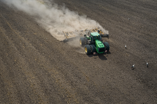 Aerial view of a tractor working the land kicking up dust in a stark contrast to the dark fertile soil Chyhyrynskyi district Cherkasy Oblast Ukraine. Aerial view of a tractor working the land kicking up dust in a stark contrast to the dark fertile soil Chyhyrynskyi district Cherkasy Oblast Ukraine.