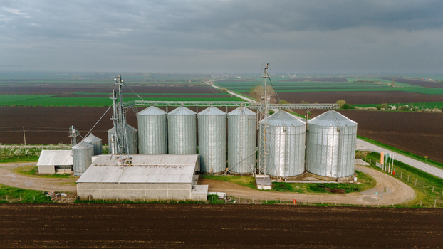 Aerial view of metallic silos standing tall amidst dark soil and green fields under a brooding sky Sremska Mitrovica Vojvodina Serbia. Aerial view of metallic silos standing tall amidst dark soil and green fields under a brooding sky Sremska Mitrovica Vojvodina Serbia.
