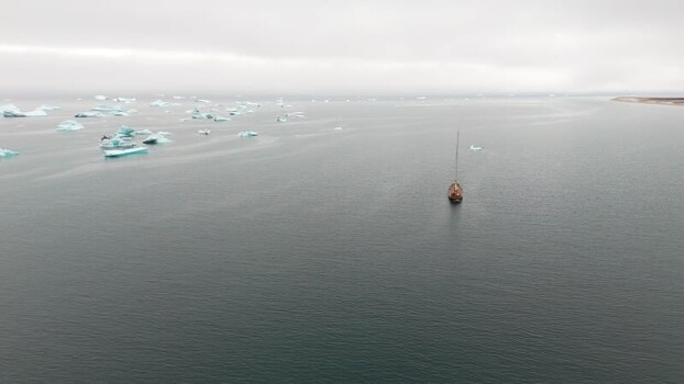 Aerial view of a wooden sailboat near icebergs Greenland. Aerial view of a wooden sailboat near icebergs Greenland.