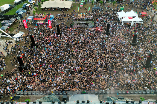 Herzogenaurach Germany 24 July 2025 Aerial view of the Open Beatz Festival featuring a massive crowd of people gathered in front of a stage with white tents and food stalls.