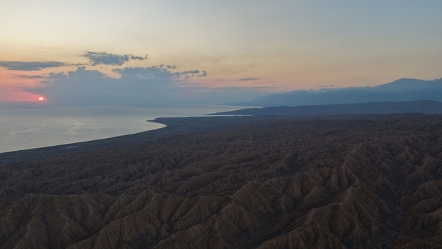 Aerial view of the rugged landscape and arid hills overlooking the calm waters of Issyk Kul at sunset in Issyk Kul Region Kyrgyzstan. Aerial view of the rugged landscape and arid hills overlooking the calm waters of Issyk Kul at sunset in Issyk Kul Region Kyrgyzstan.