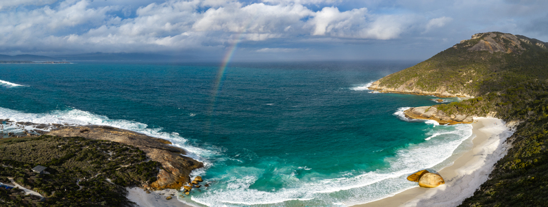 Aerial view of Two Peoples Bay Nature Reserve with a rainbow over the turquoise ocean white sandy beach and rocky coastline in Albany Western Australia Australia.