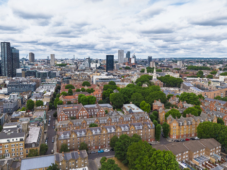 Aerial view of Shoreditch featuring dense urban architecture red brick buildings lush trees and a skyline with modern skyscrapers in London England United Kingdom. Aerial view of Shoreditch featuring dense urban architecture red brick buildings lush trees and a skyline with modern skyscrapers in London England United Kingdom.