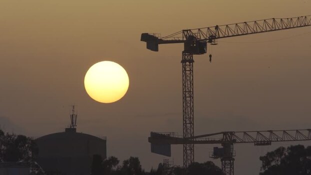 Aerial view of construction cranes at sunset in Algeria.