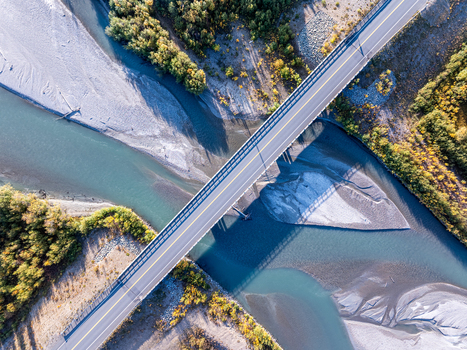 Aerial view of the Tok River bridge crossing the riverbed with surrounding autumn forest in Southeast Fairbanks Census Area Alaska United States.