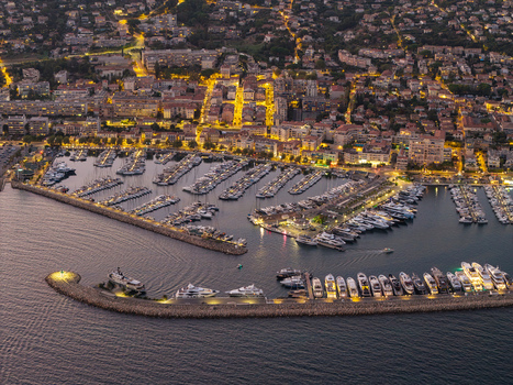Aerial view of the illuminated Port Vauban marina filled with luxury yachts and boats with glowing city lights reflecting on the water in Antibes Provence Alpes Cote d Azur France. Aerial view of the illuminated Port Vauban marina filled with luxury yachts and boats with glowing city lights reflecting on the water in Antibes Provence Alpes Cote d Azur France.