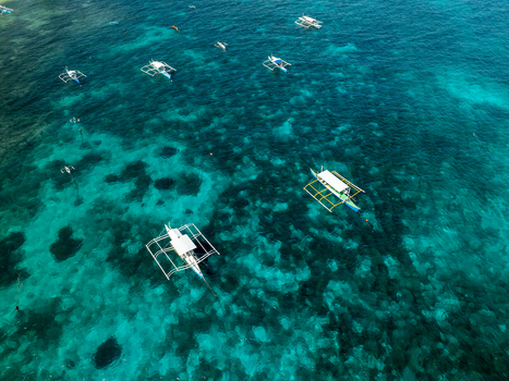 Aerial view of Naked Island surrounded by turquoise waters with traditional outrigger boats floating in the sea in Siargao Philippines. Aerial view of Naked Island surrounded by turquoise waters with traditional outrigger boats floating in the sea in Siargao Philippines.