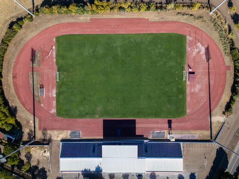Aerial view of a football field with a green pitch and red running track surrounded by stadium seating and floodlights in Elvas Portalegre Portugal. Aerial view of a football field with a green pitch and red running track surrounded by stadium seating and floodlights in Elvas Portalegre Portugal.