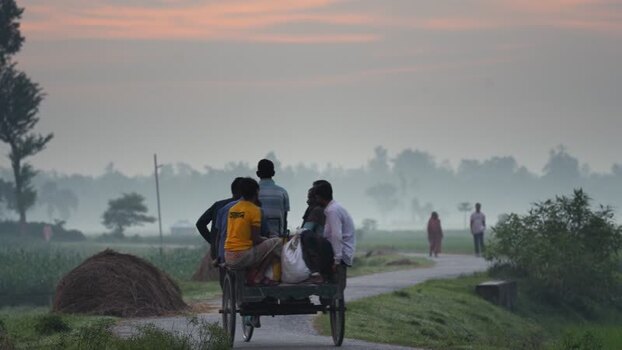 View of people riding a van on a rural road at dawn Bangladesh. View of people riding a van on a rural road at dawn Bangladesh.