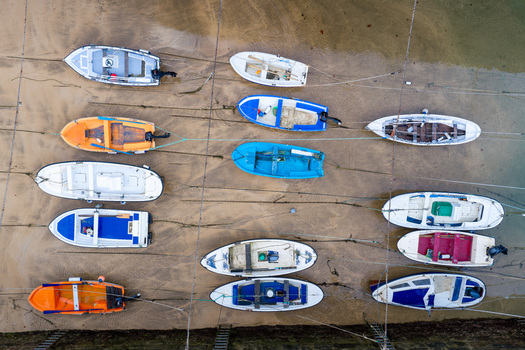 Aerial view of Puerto de Zarautz with colorful fishing boats moored on the sandy beach at low tide in Zarautz Basque Country Spain.