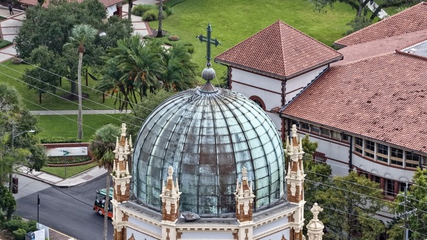 Aerial view of Memorial Presbyterian Church with its copper dome and ornate architectural details surrounded by palm trees and tiled rooftops in St. Augustine Florida United States.