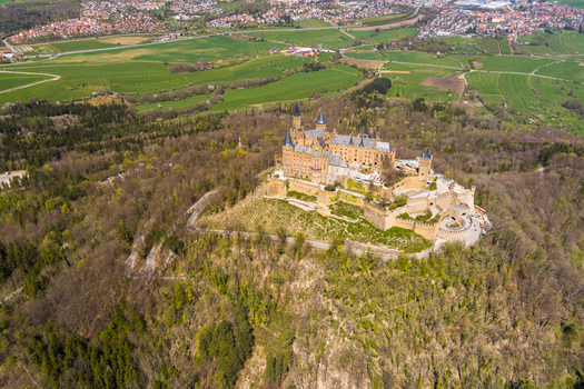 Burg Hohenzollern Germany 27 September 2026 Aerial view of Hohenzollern Castle perched on a hilltop surrounded by dense forest and rolling green fields in the Swabian Jura.