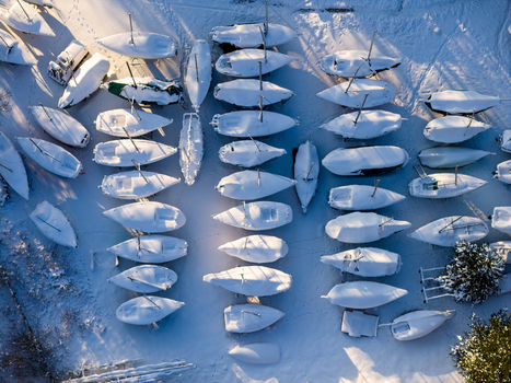 Aerial view of many sailboats parked on land and covered in thick white snow during a sunny winter day Trakai Vilnius County Lithuania. Aerial view of many sailboats parked on land and covered in thick white snow during a sunny winter day Trakai Vilnius County Lithuania.