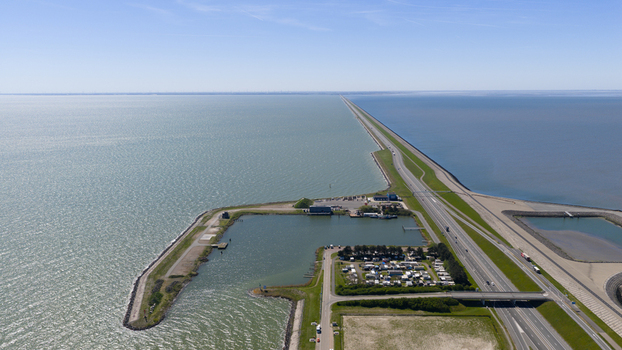 Aerial view of the Breezanddijk artificial island and Afsluitdijk causeway separating the Wadden Sea and IJsselmeer with a harbor and highway in Breezanddijk Friesland Netherlands.