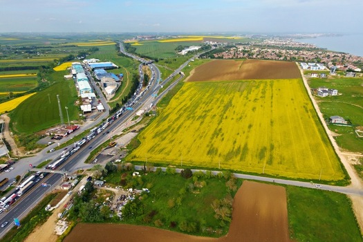 Aerial view of a highway with heavy traffic congestion next to vibrant yellow canola fields and industrial buildings Silivri Istanbul Turkey. Aerial view of a highway with heavy traffic congestion next to vibrant yellow canola fields and industrial buildings Silivri Istanbul Turkey.