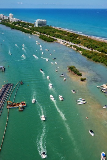 Aerial view of numerous boats cruising through turquoise waters along a lush green shoreline with the ocean in the distance Jupiter Florida United States. Aerial view of numerous boats cruising through turquoise waters along a lush green shoreline with the ocean in the distance Jupiter Florida United States.