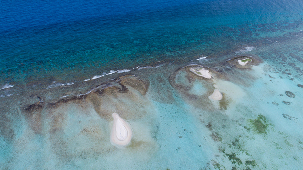 Aerial view of Los Roques archipelago featuring small sandy cays surrounded by vibrant turquoise water and coral reefs in Los Roques Dependencias Federale Venezuela. Aerial view of Los Roques archipelago featuring small sandy cays surrounded by vibrant turquoise water and coral reefs in Los Roques Dependencias Federale Venezuela.