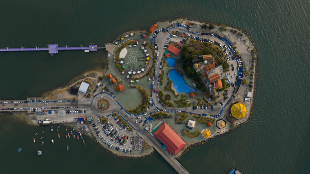 Aerial view of Koh Loi island featuring temple buildings a swimming pool parking areas and a long bridge connecting to the mainland in Si Racha Chon Buri Thailand. Aerial view of Koh Loi island featuring temple buildings a swimming pool parking areas and a long bridge connecting to the mainland in Si Racha Chon Buri Thailand.