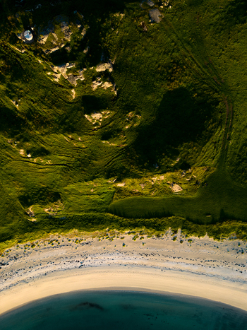 Aerial view of the sandy shoreline at Tangstad beach meeting lush green hills and turquoise water in Leknes Nordland Norway. Aerial view of the sandy shoreline at Tangstad beach meeting lush green hills and turquoise water in Leknes Nordland Norway.