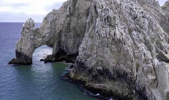Aerial view of The Arch of Cabo San Lucas a natural rock formation rising from turquoise waters with rugged cliffs and sandy beaches in Cabo San Lucas Baja California Sur Mexico.