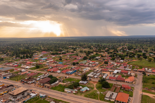 Aerial view of Katakwi Town Council with residential buildings red rooftops and roads under a dramatic stormy sky with sun rays in Katakwi Eastern Region Uganda. Aerial view of Katakwi Town Council with residential buildings red rooftops and roads under a dramatic stormy sky with sun rays in Katakwi Eastern Region Uganda.