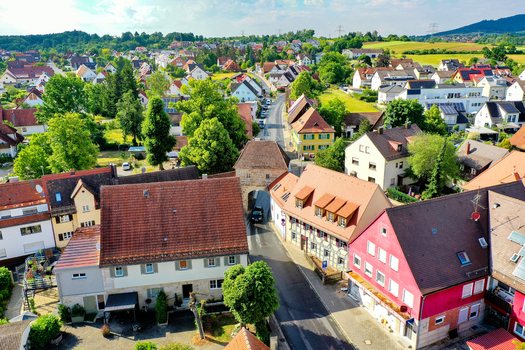 Aerial view of the historic town center with traditional red tiled roofs lush green trees and the medieval stone gate tower in Neunkirchen am Brand Bavaria Germany. Aerial view of the historic town center with traditional red tiled roofs lush green trees and the medieval stone gate tower in Neunkirchen am Brand Bavaria Germany.