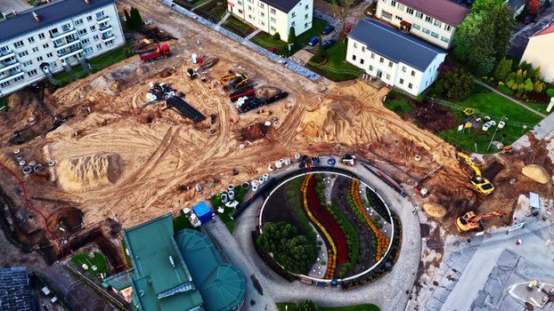 Aerial view of a construction site with heavy machinery excavators and piles of earth surrounding a circular landscaped garden bed in a residential area in Latvia. Aerial view of a construction site with heavy machinery excavators and piles of earth surrounding a circular landscaped garden bed in a residential area in Latvia.